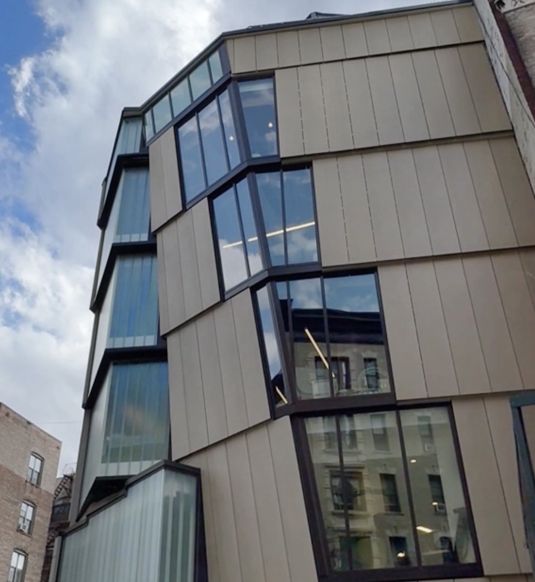 The angled glass-and-panel facade of The Brotherhood Sister Sol's Harlem building, seen from street level